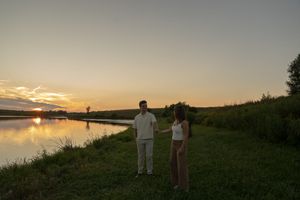 Two figures stand together on a hill against a golden sunset sky.