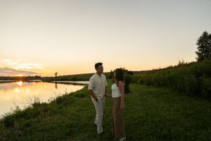 A couple embraces on a scenic hilltop during golden hour.