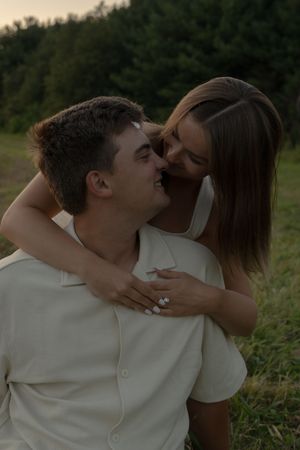 A romantic couple in white clothing shares an intimate moment in a grassy field.