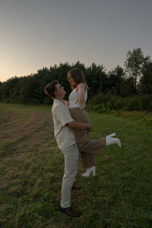 A couple in coordinated white outfits shares a romantic moment outdoors.