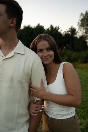 A couple in matching white outfits poses together in a summer field.
