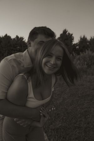 A joyful couple shares laughter while sitting in a grassy field.