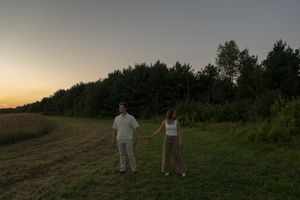 Silhouettes of two people standing together in a field during golden hour.