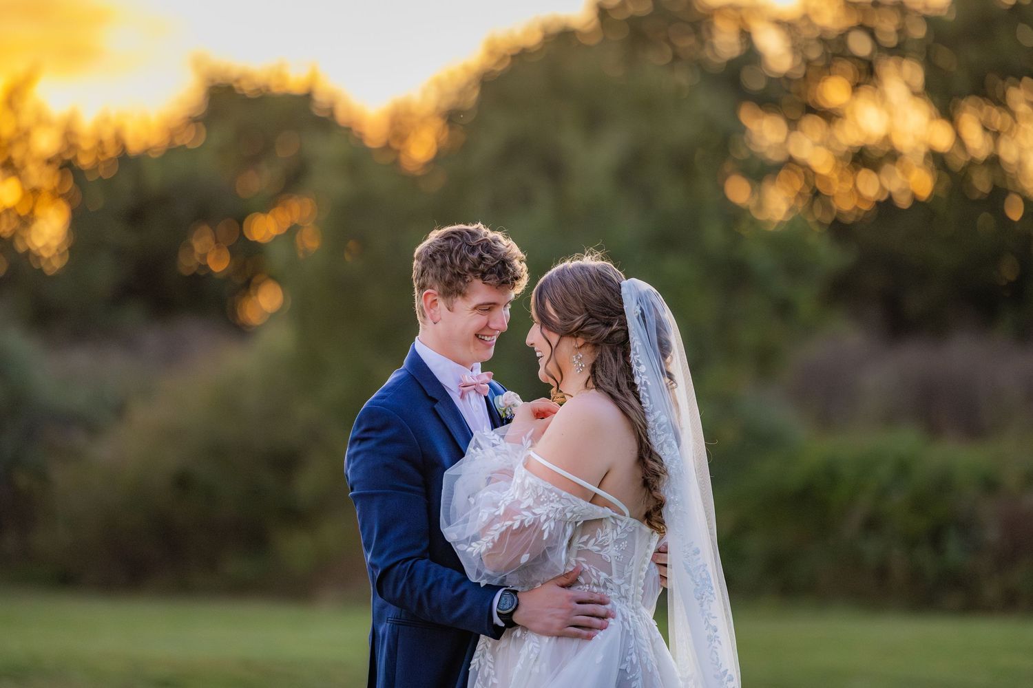 Newlyweds share an intimate embrace in front of a sunset during their golden hour wedding photo session.
