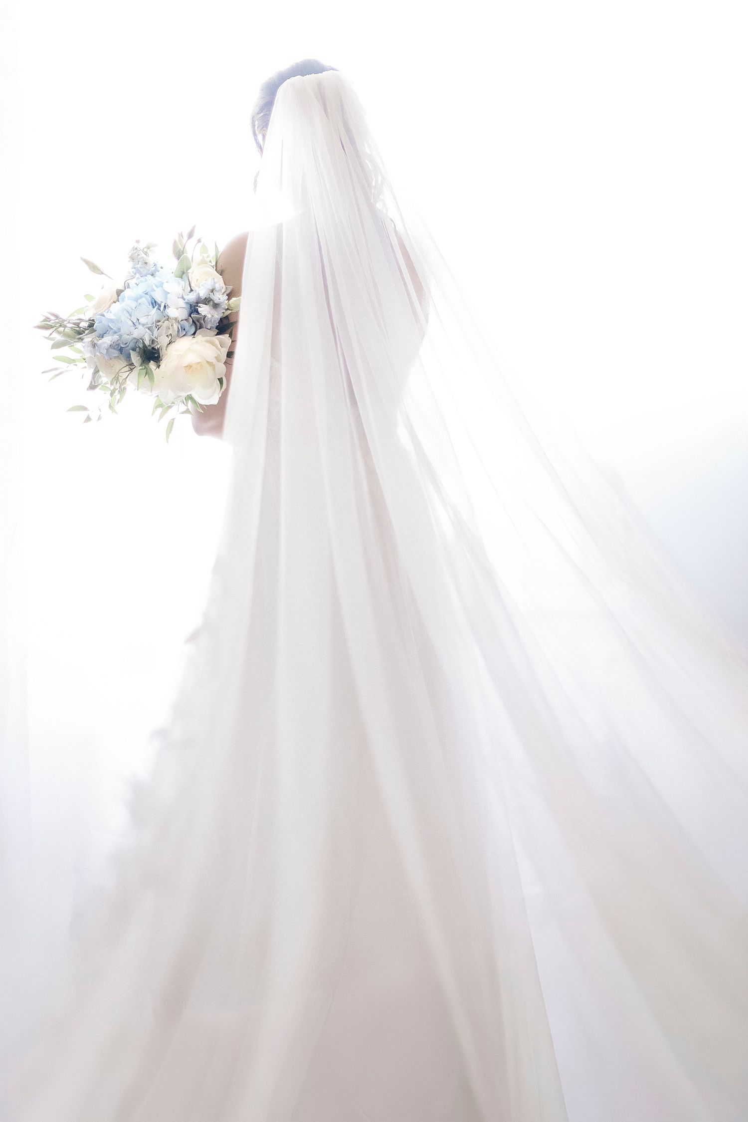 White wedding dress details with delicate lace and tulle fabric flowing elegantly against a light background.