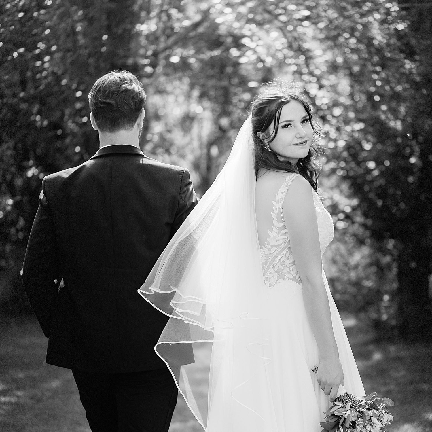 Photographe mariage Montauban – portrait en noir et blanc d’une mariée élégante au bras de son époux, capturé par Laëtitia Klopocki.