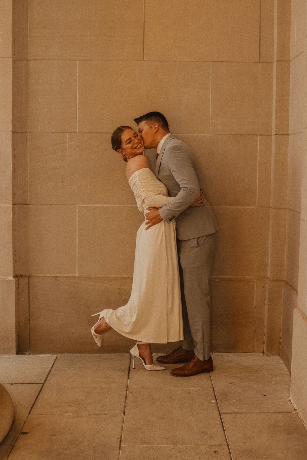Romantic wedding couple shares intimate moments against stone wall backdrop.