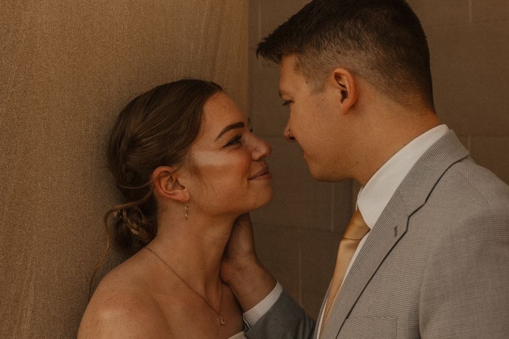 Couple in wedding attire shares tender moments in warm-toned indoor setting.