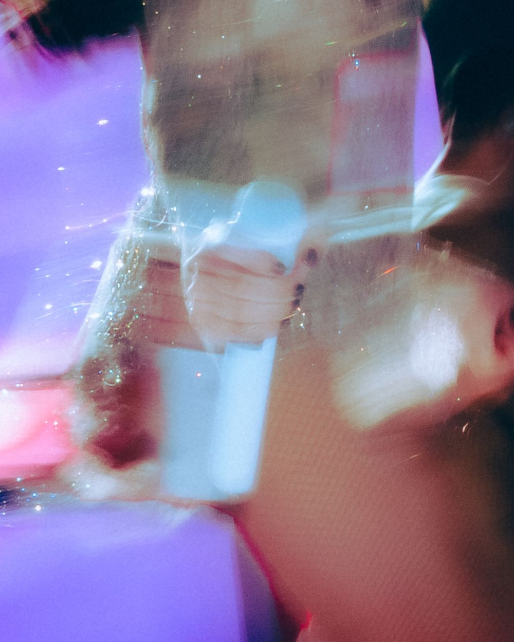 Abstract double exposure portrait with purple and blue light leaks creating a dreamy, ethereal effect.