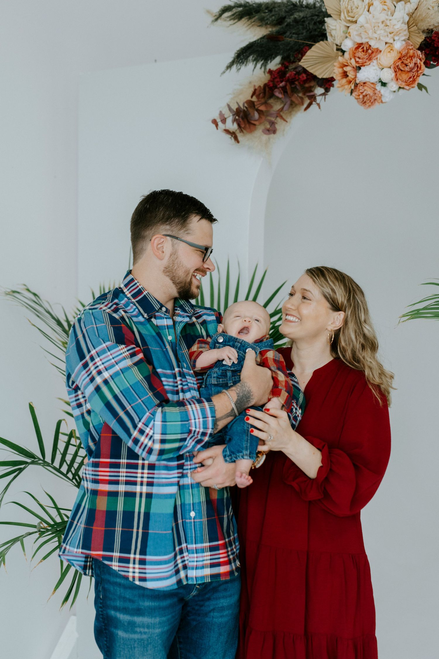 A couple in plaid shirt and red sweater share intimate moments while drinking coffee in a bright indoor setting.