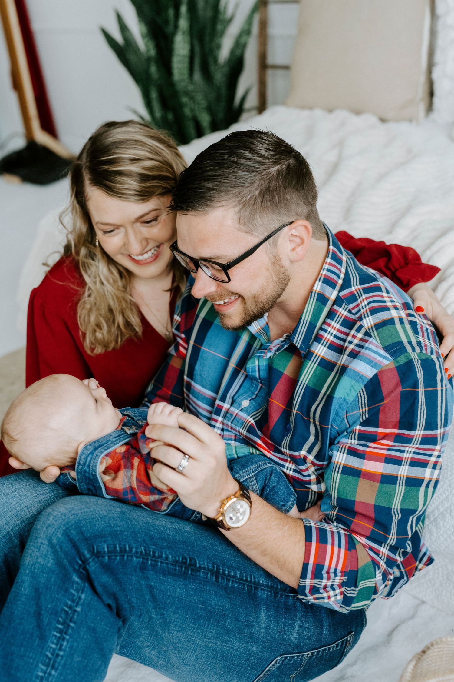 A couple in plaid and denim cuddle together on white bedding in a series of intimate lifestyle photos.