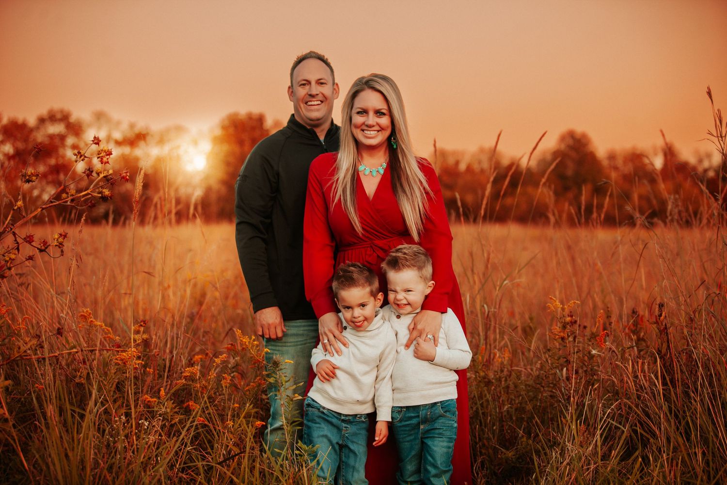 Family portrait captured in a golden field during magical sunset hour.
