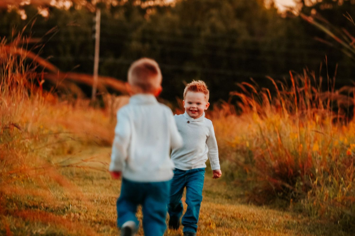 Family shares joyful moments together in sun-kissed autumn field.