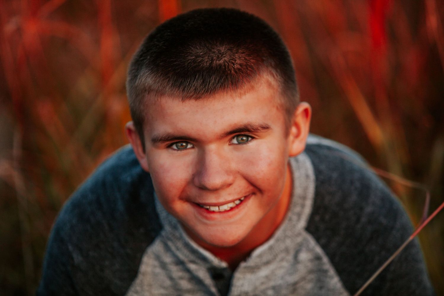 Portrait of someone in casual attire against an autumn backdrop with warm lighting.
