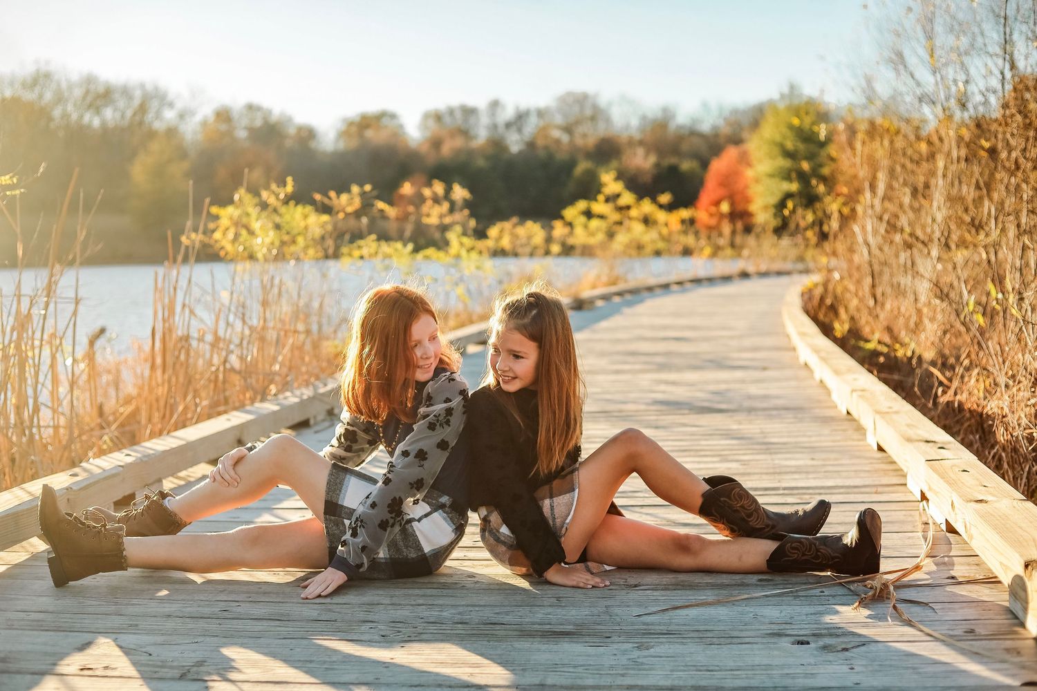 Two people relax on a wooden boardwalk during a bright autumn day.