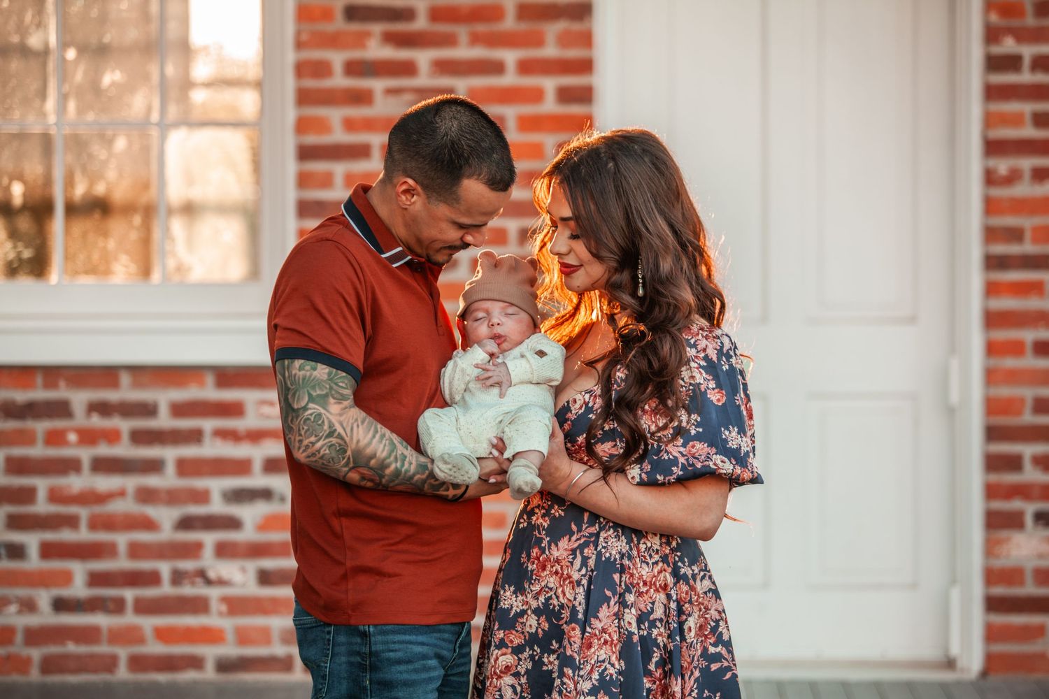A family shares an intimate moment on their front porch steps with their newborn baby.