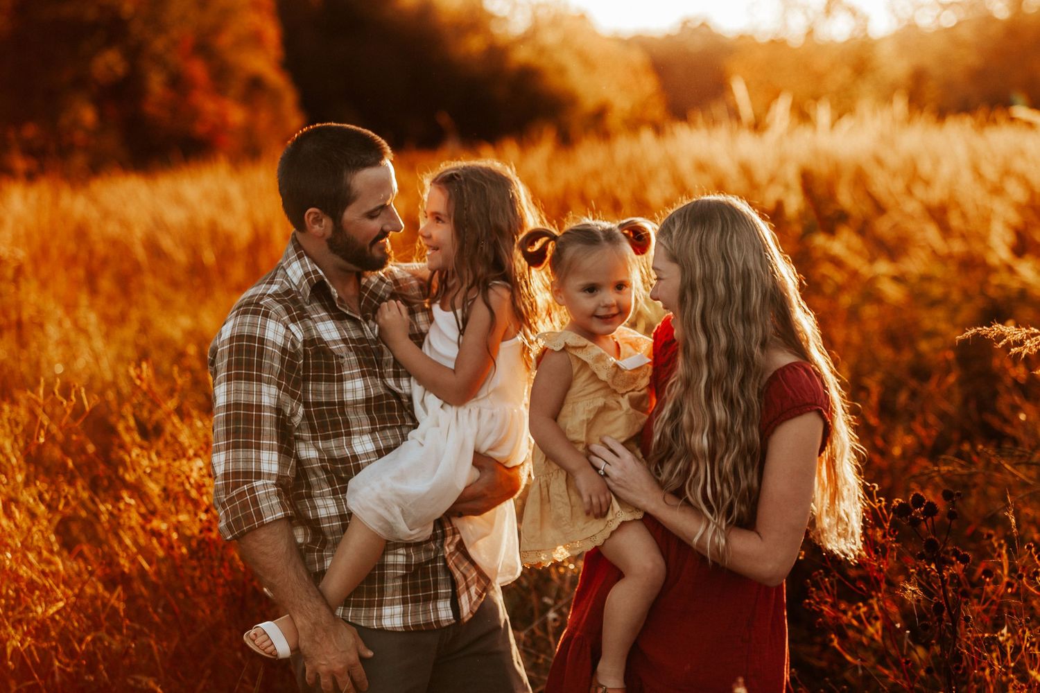 Couple embraces in a rustic field bathed in warm sunset light.