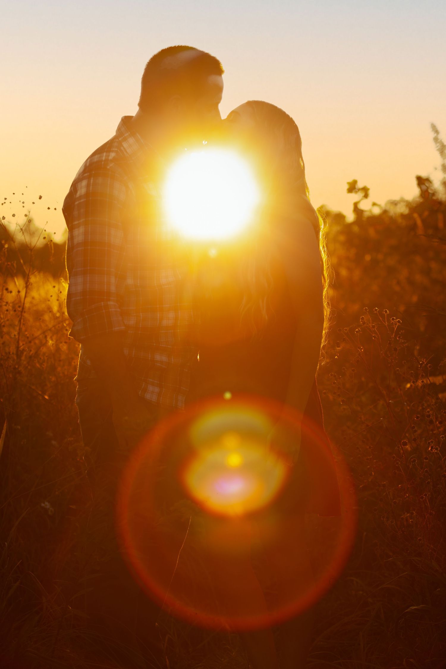 Romantic silhouettes against dramatic sunset create intimate moment in nature.