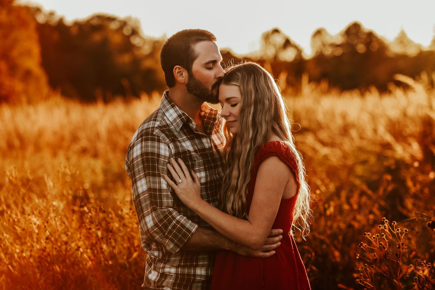 Tender embrace captured in golden sunset light among wild grasses.