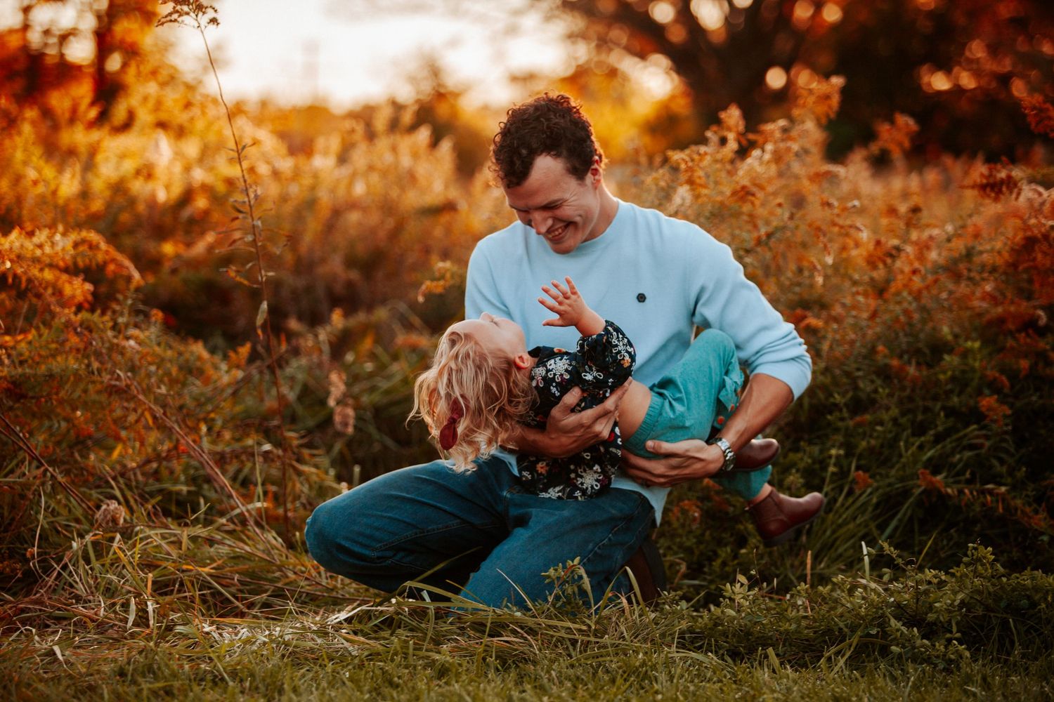 A tender moment captured between two people sitting in tall grass during sunset.