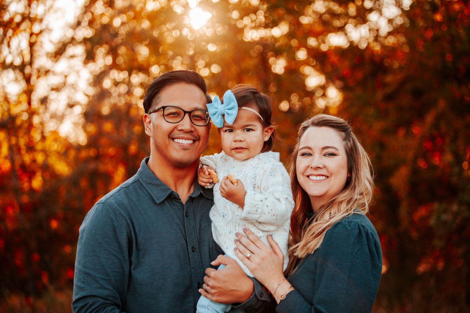Family portrait during golden hour with autumn colors in background.
