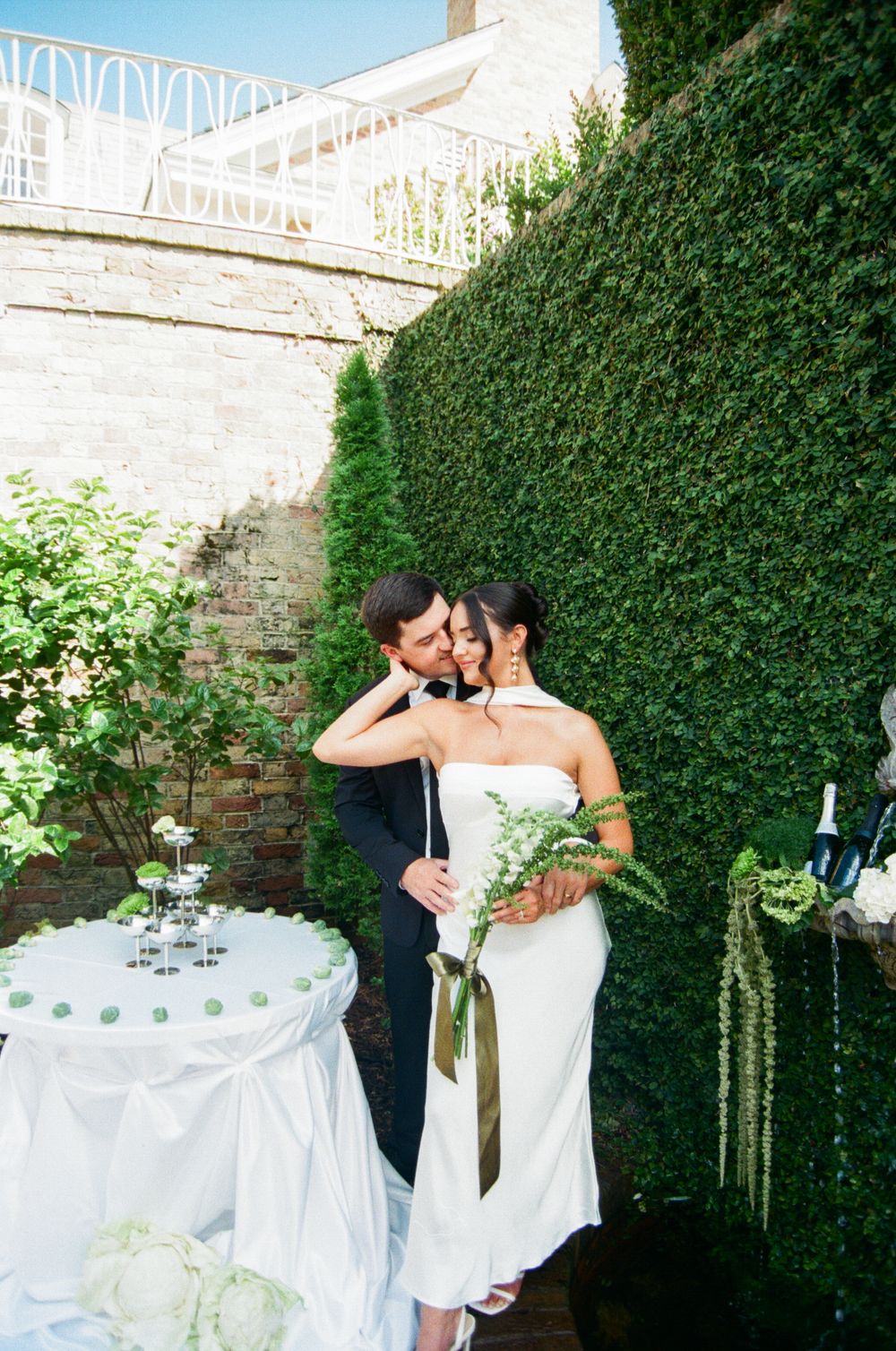 A romantic moment captured at an outdoor garden wedding reception with white tablecloths and hanging decorations.