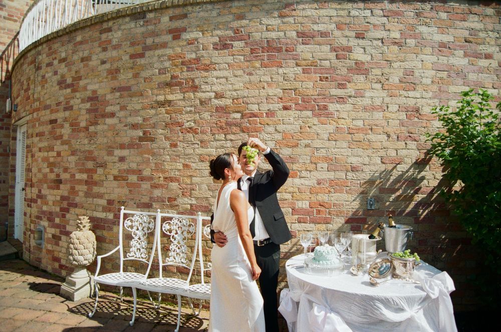 A romantic outdoor wedding reception setup with elegant place settings along a curved brick wall.