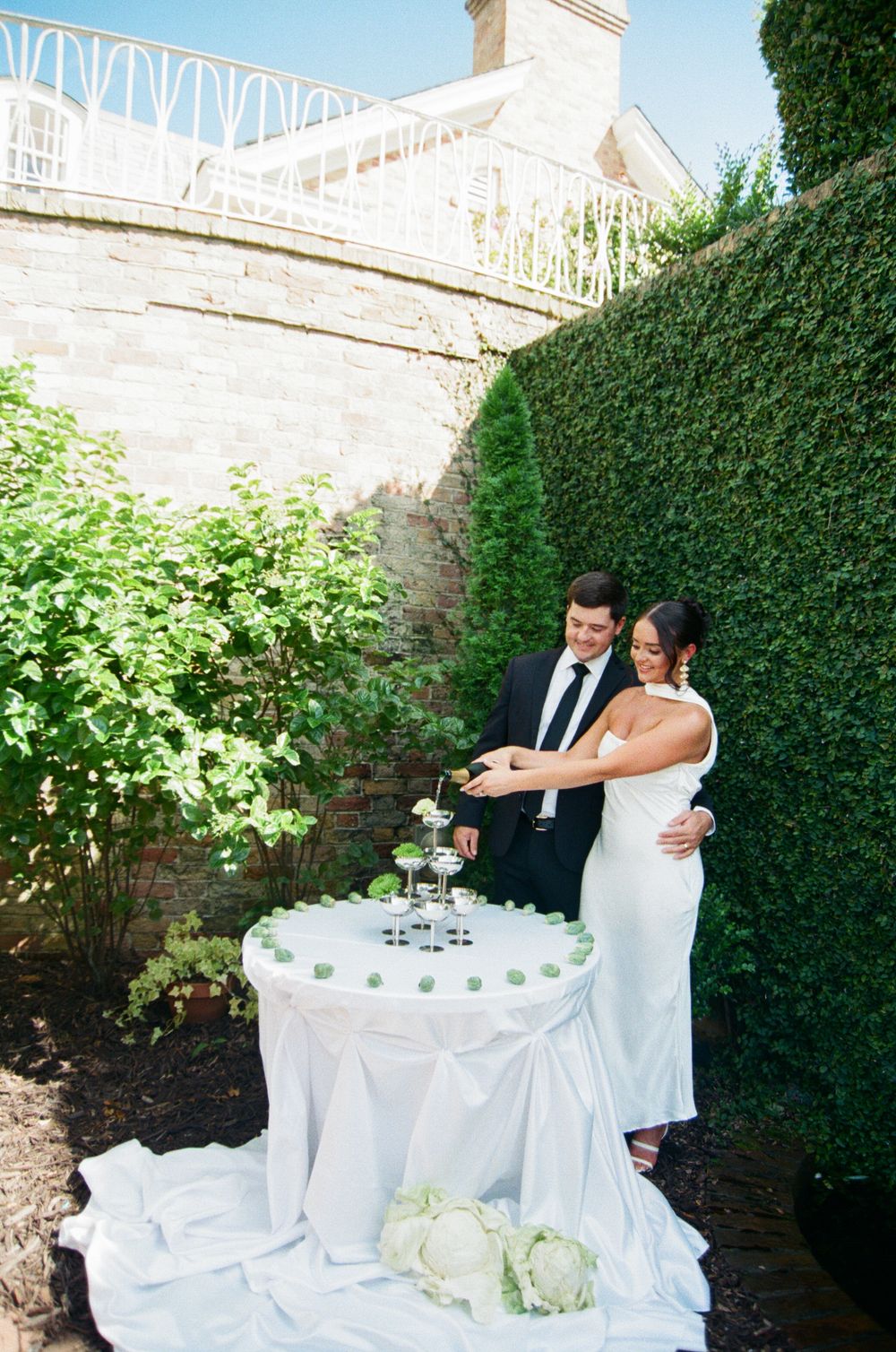Garden party setup with elegant white-draped tables and ivy-covered walls creating an intimate outdoor atmosphere.