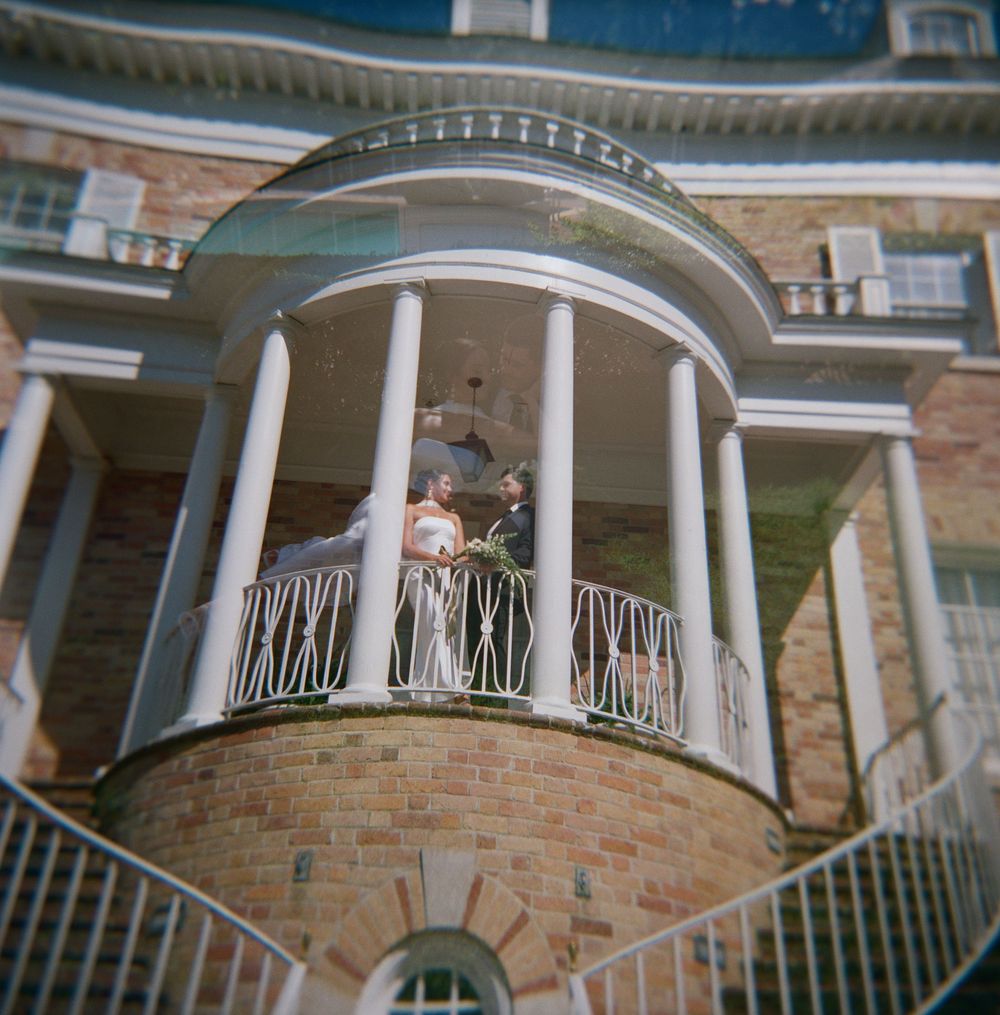 Classic architectural detail of multiple semicircular porches with white columns and metal railings on a brick building.