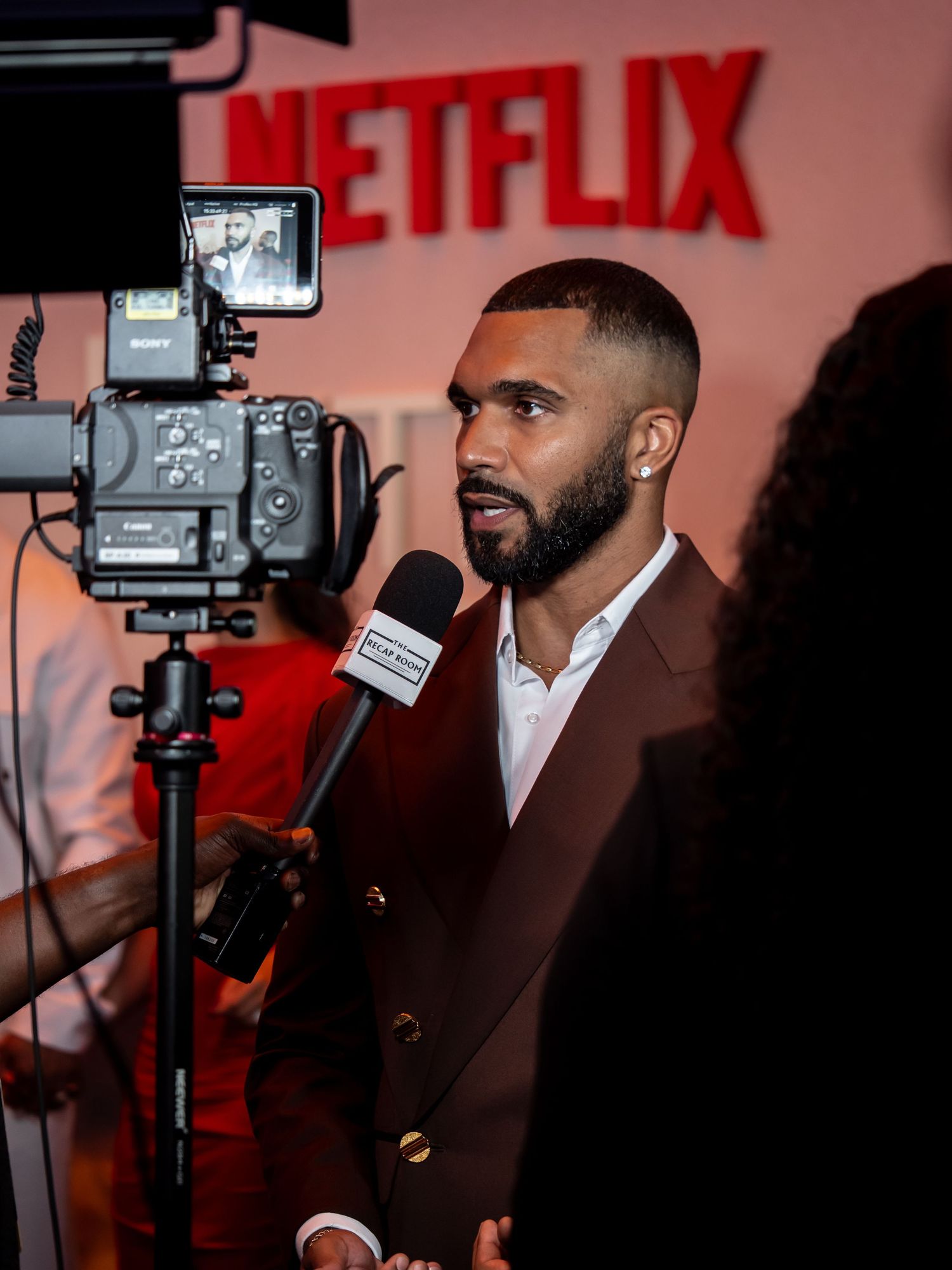 Media interview session against Netflix branded backdrop with professional camera equipment.