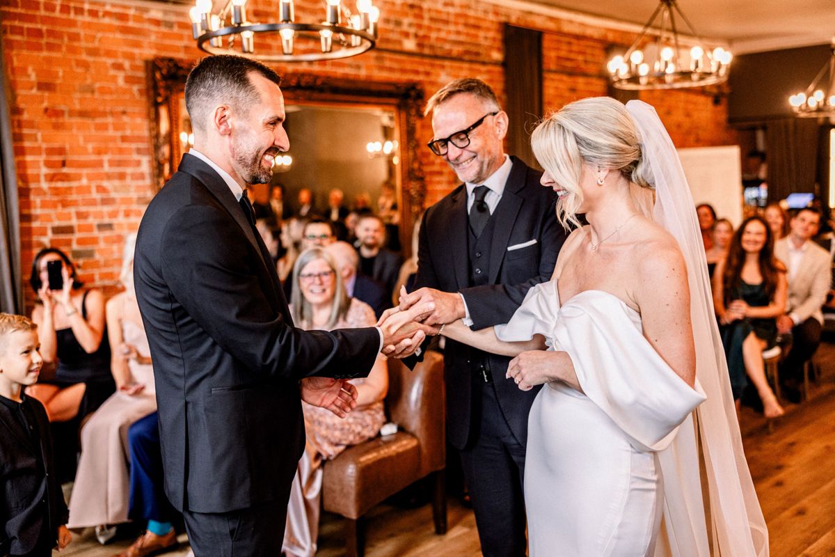 Bride and groom walking hand in hand near lakefront venue in Ontario
