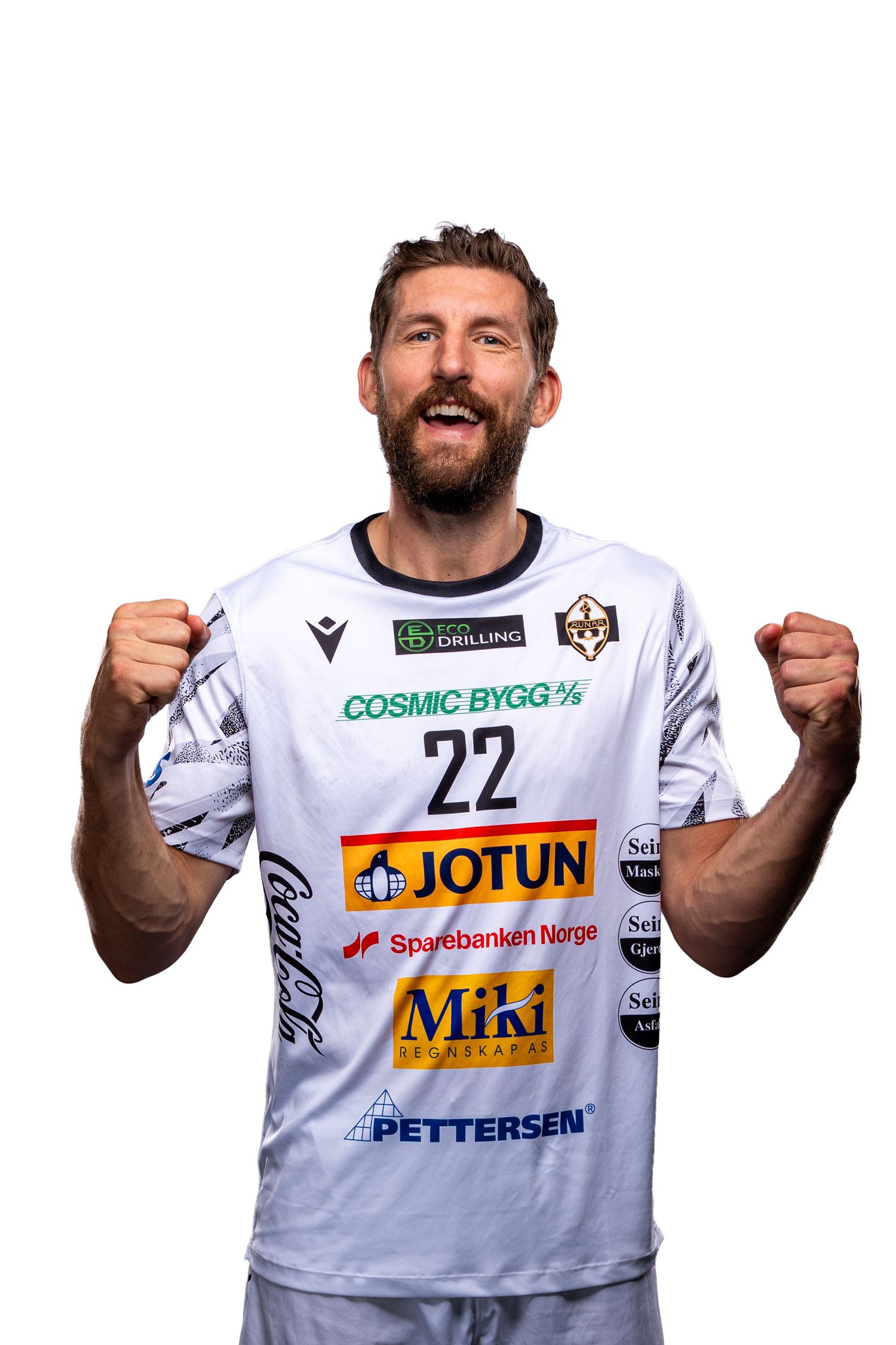 Athletic player in white jersey with Jotun and MIA sponsors poses with raised fists in celebration pose.