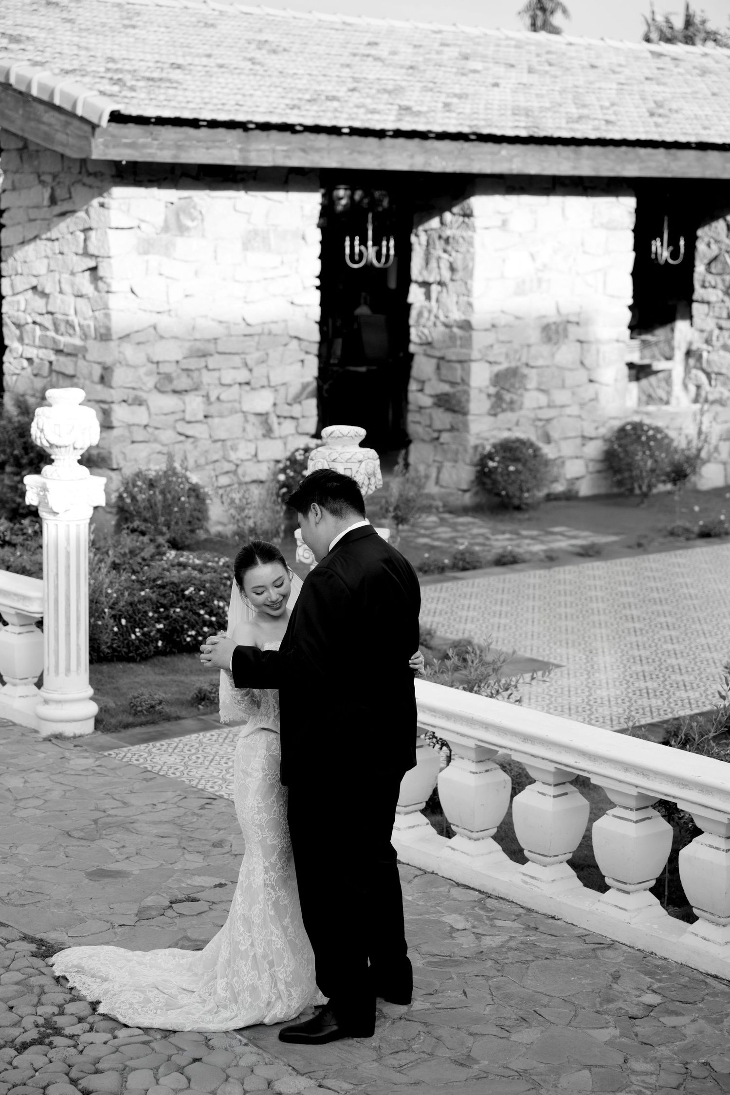 Black and white photo of bride and groom sharing intimate moment at elegant stone venue.