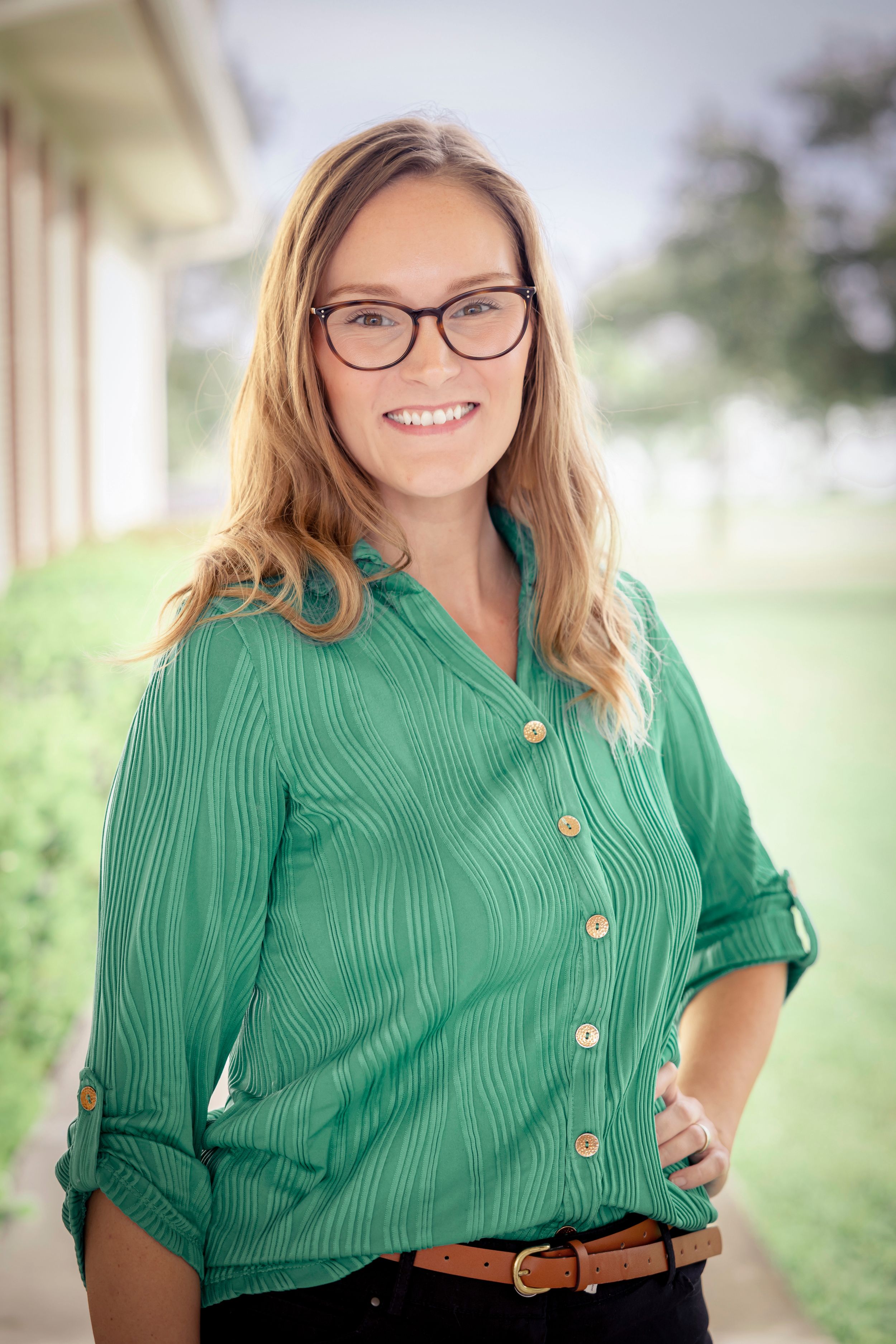 Professional portrait of a woman in glasses and a green blouse outdoors