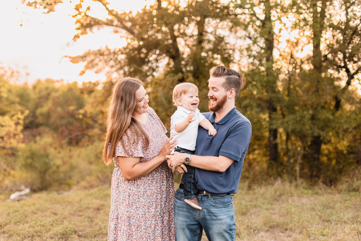 A family walking together on a dirt trail through a grassy field at sunset.