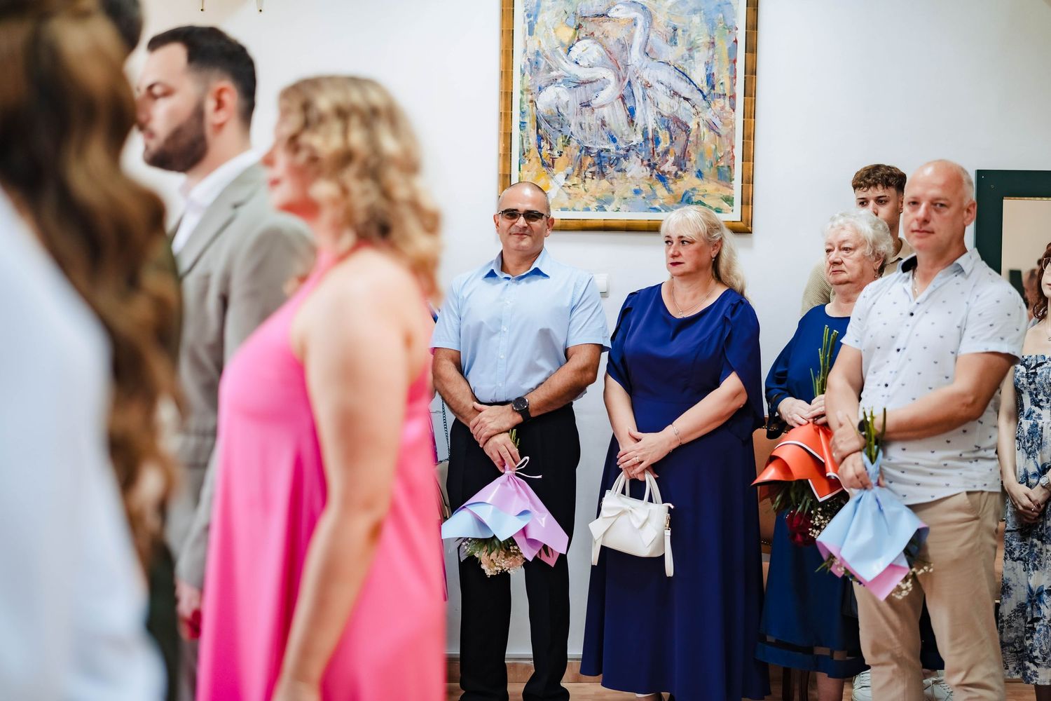 Wedding guests gather in a bright indoor venue with artwork on the walls during a celebration.
