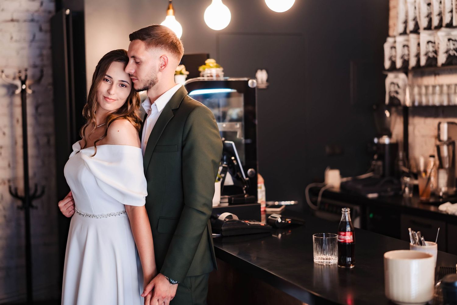 Romantic moments captured in dimly lit bar setting with pendant lights and dark ambiance.
