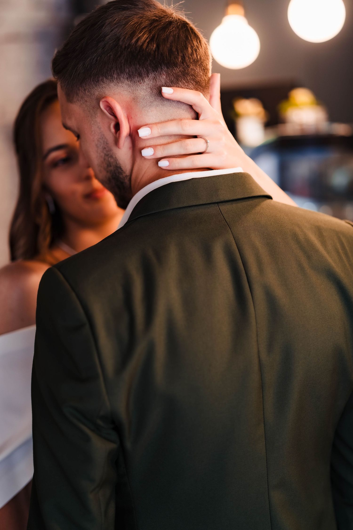 Close-up details of couple embracing in formal attire against dark background.