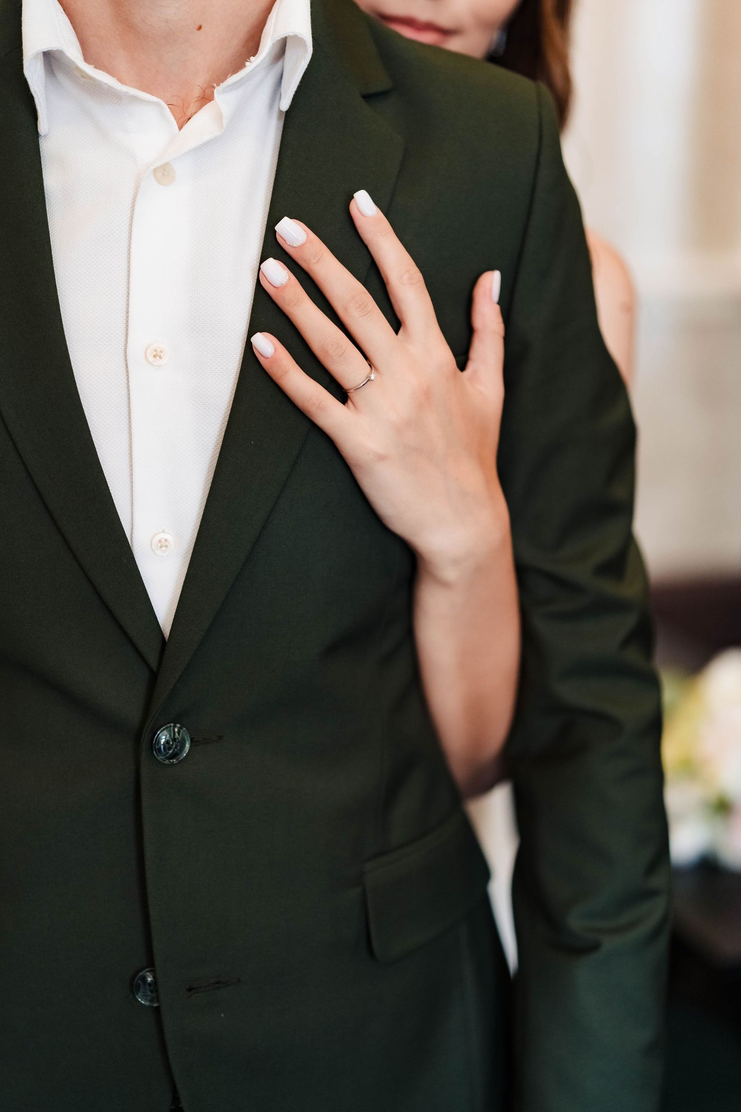 Close-up of formal dark suit jacket with hand placement detail.