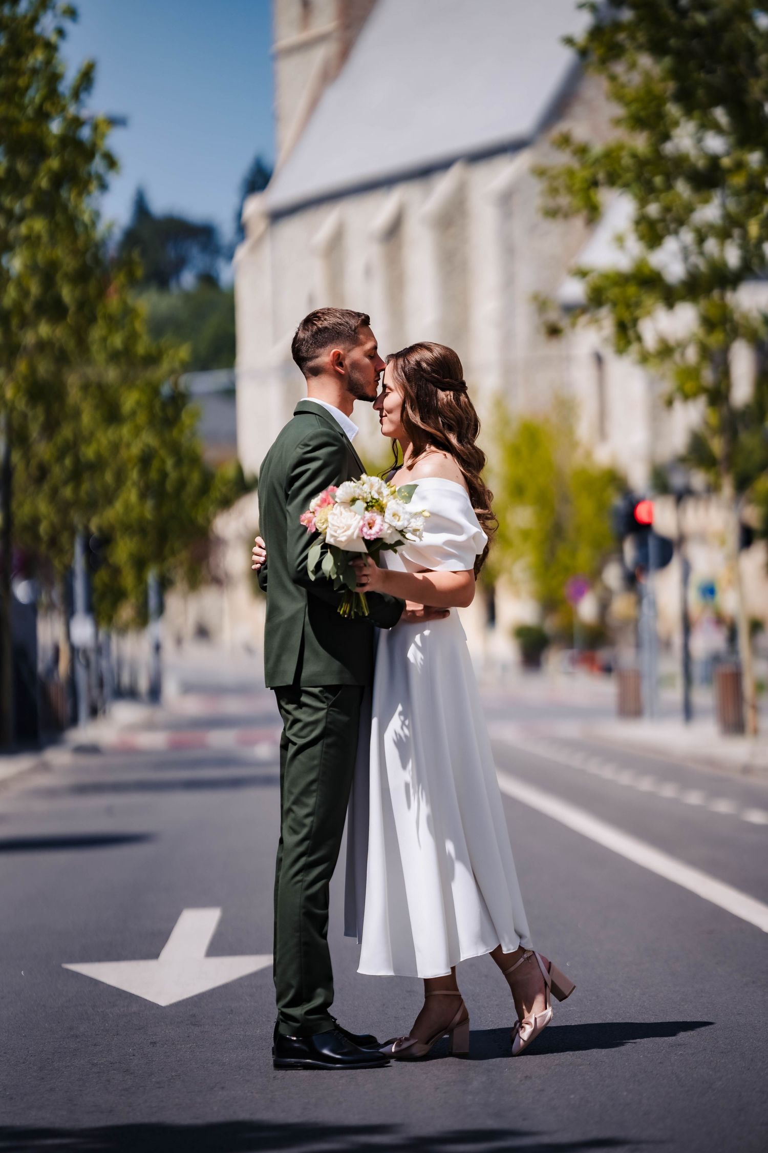 Couple shares romantic moments on an empty street with a church in the background.
