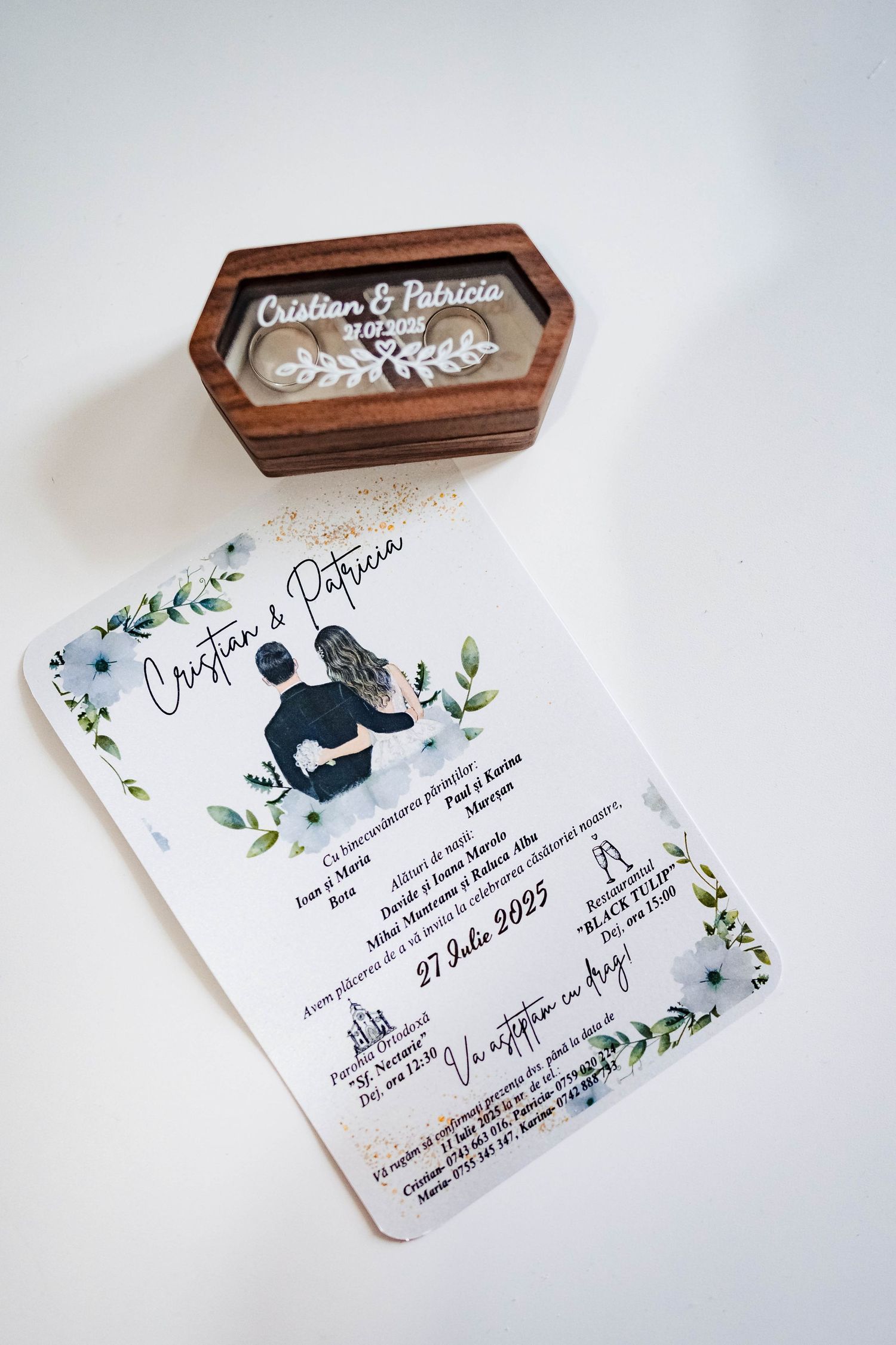 Wedding invitations with floral designs and wooden box displayed on white background.