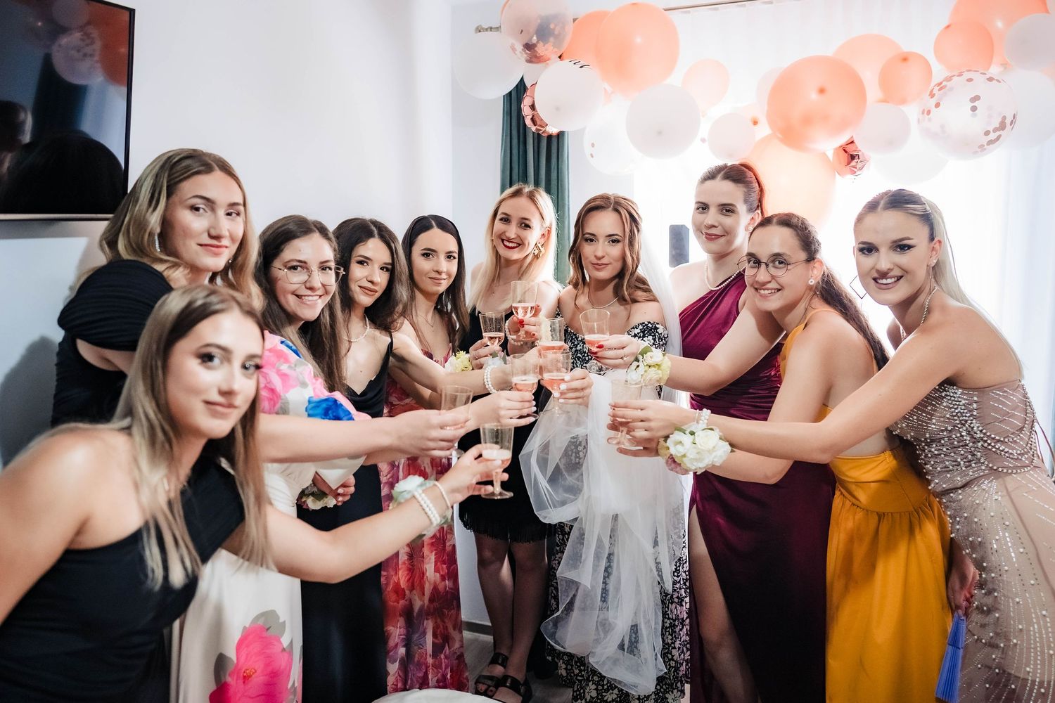 Group celebrates with drinks at a bridal party gathering with peach-colored decorations.