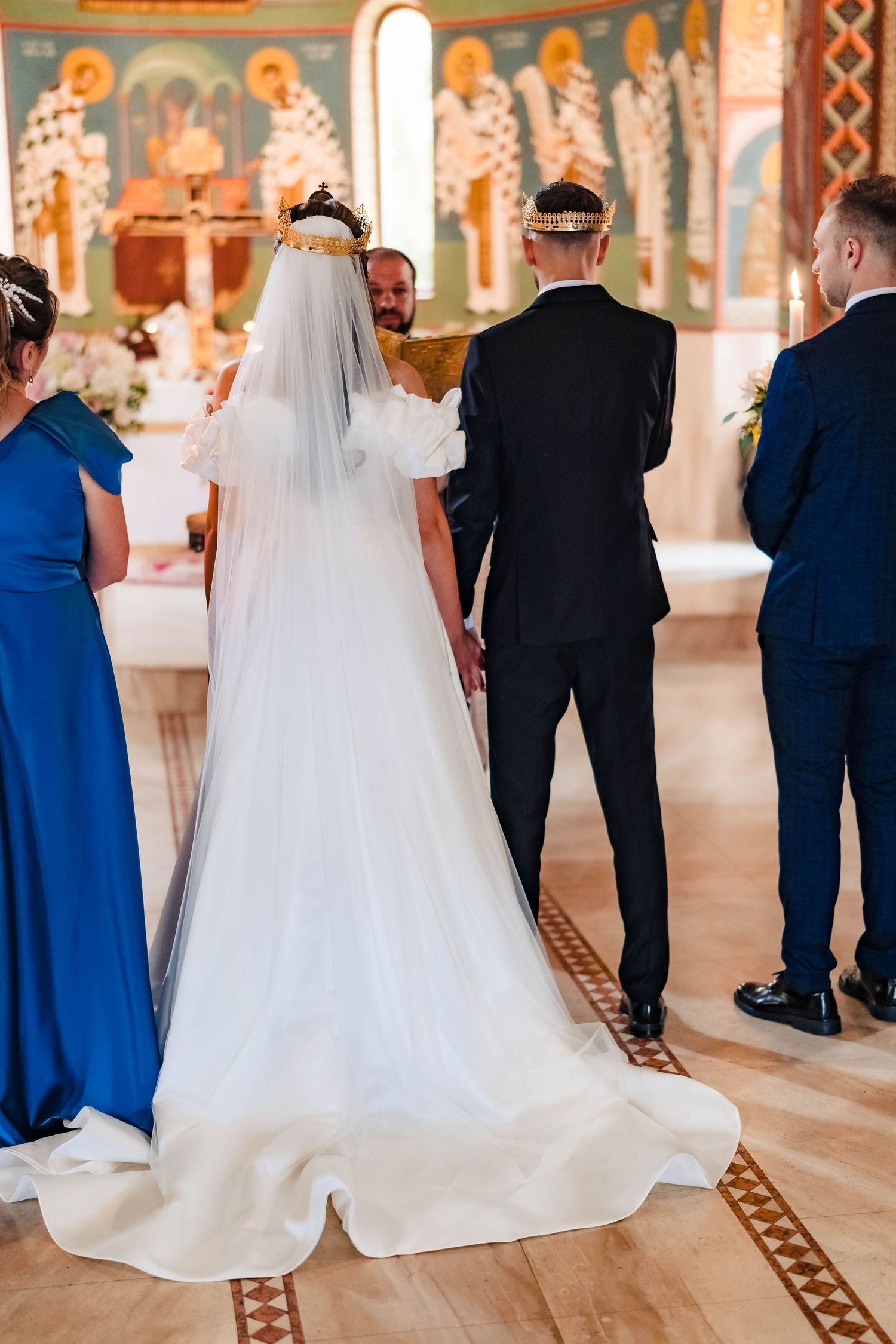 Wedding party walking through an ornate church hallway with decorative walls and flooring.