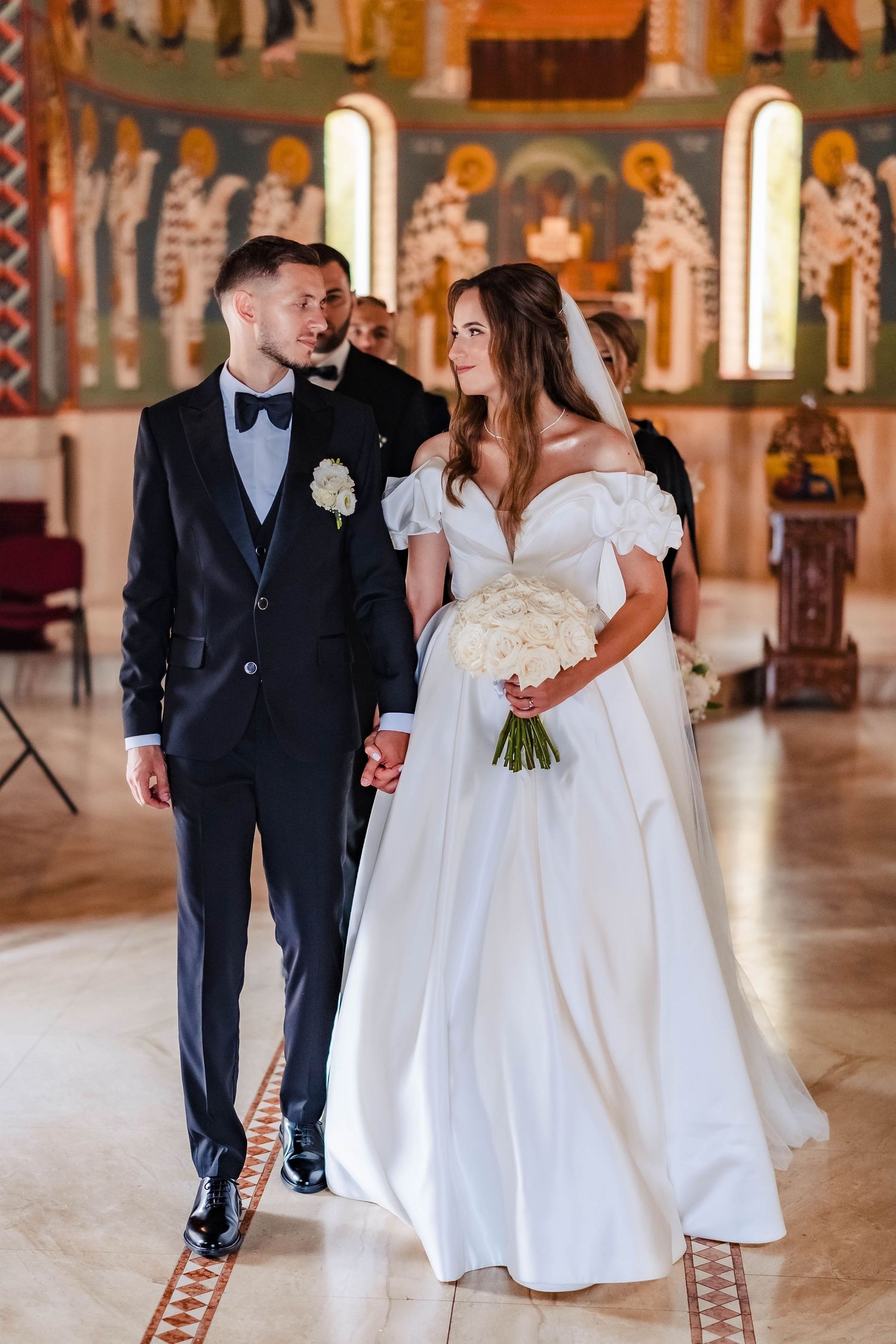 Elegant wedding ceremony in a grand church with ornate architecture and marble floors.