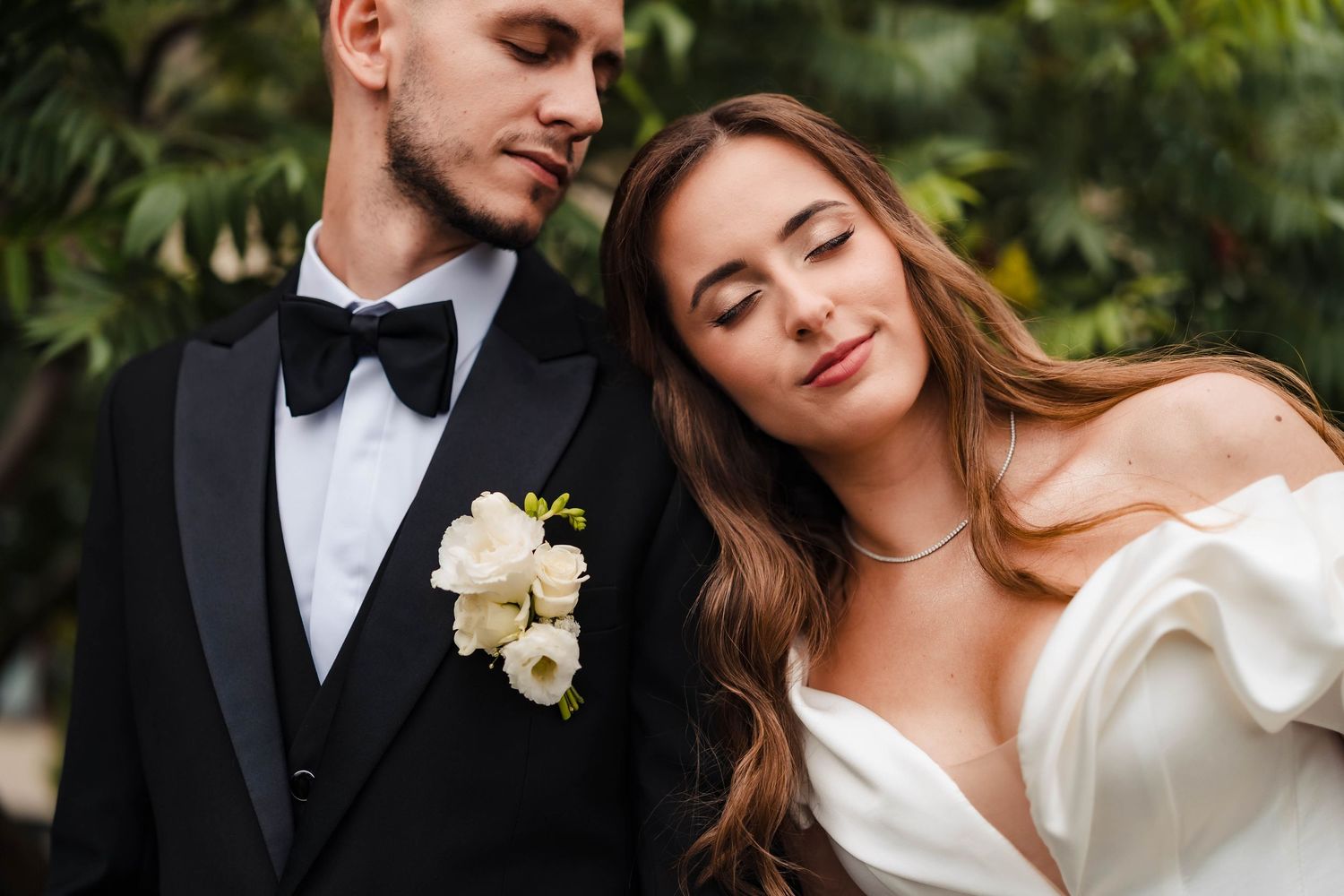 Elegant wedding portraits in garden setting with formal attire and white floral accents.