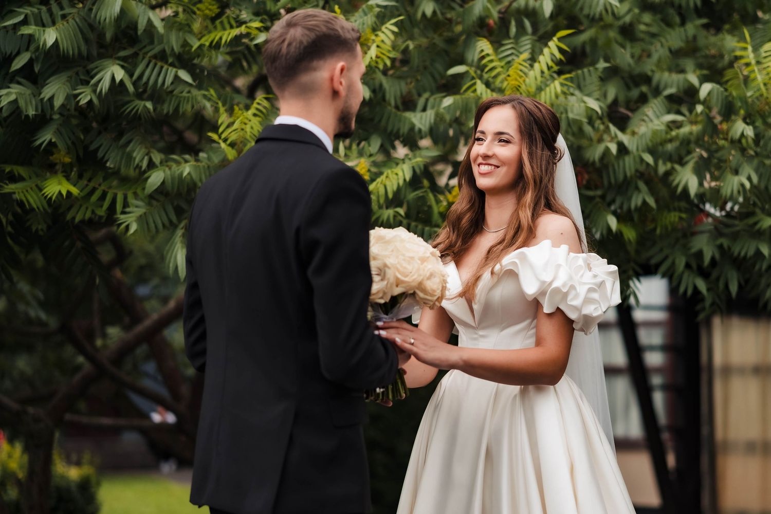 Newlyweds share intimate moments during their wedding photoshoot surrounded by tropical foliage.
