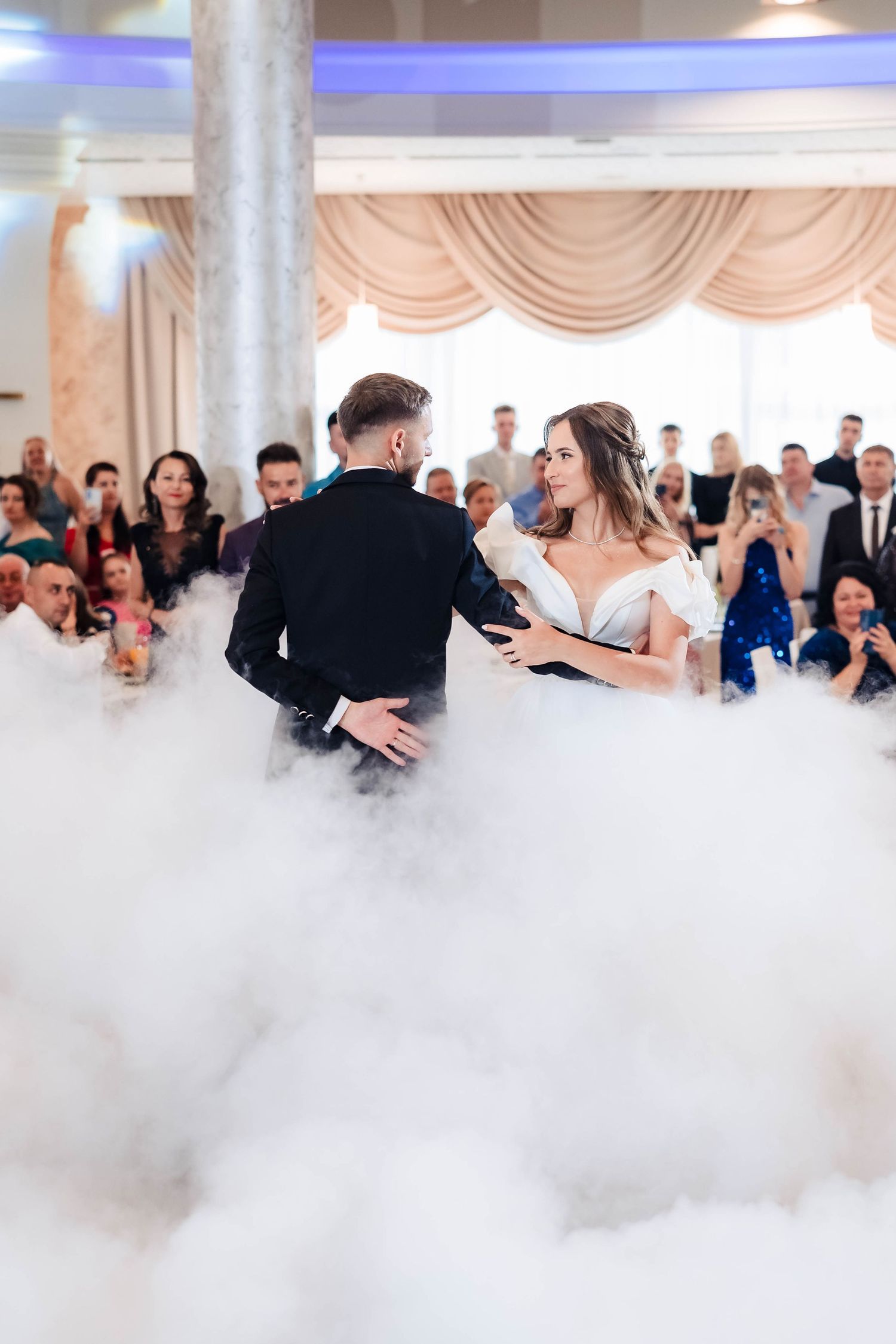First dance at wedding reception with dramatic fog effect on ballroom floor.