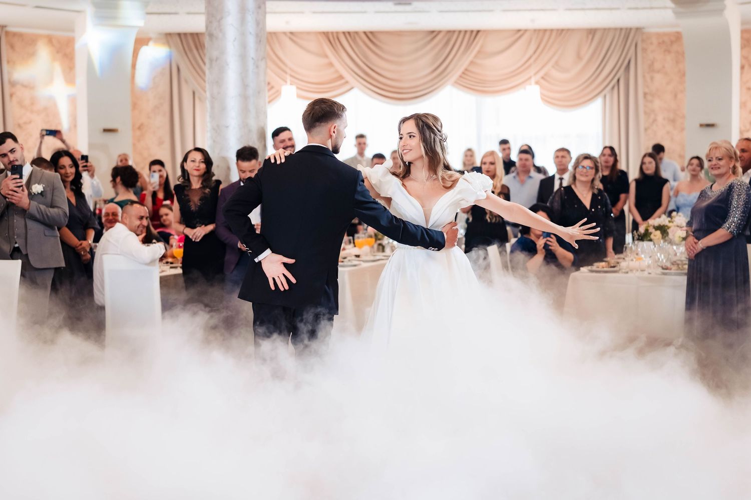 Wedding reception venue with dramatic fog effects and elegant draping decorations.