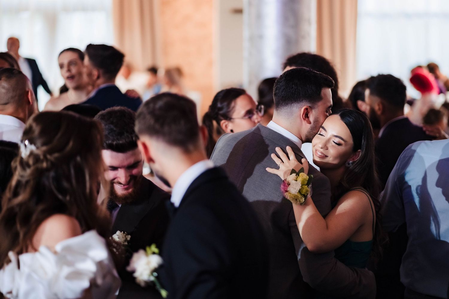 Joyful wedding reception celebration with guests dancing and laughing.