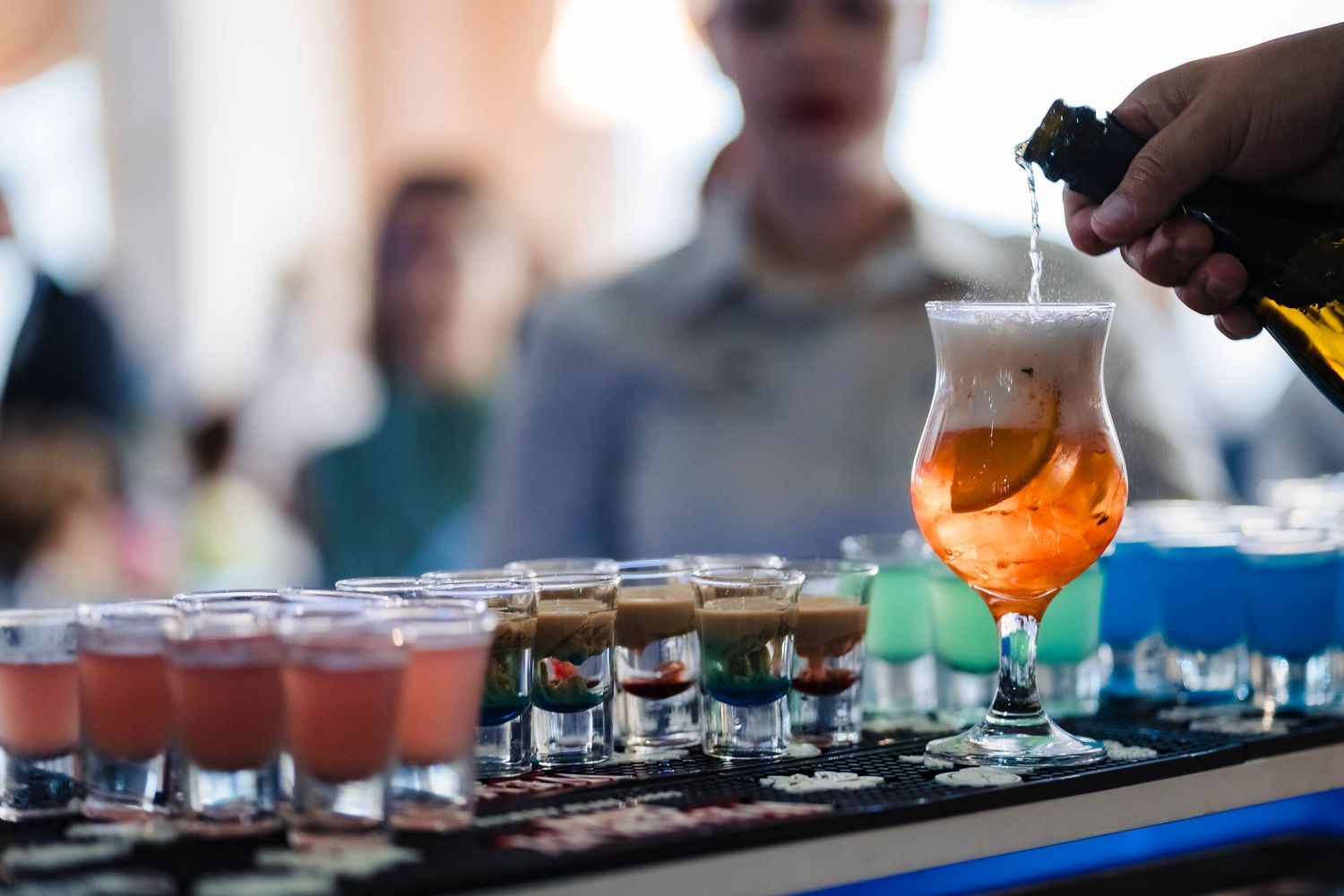 Close-up of colorful cocktails being prepared at wedding reception bar.